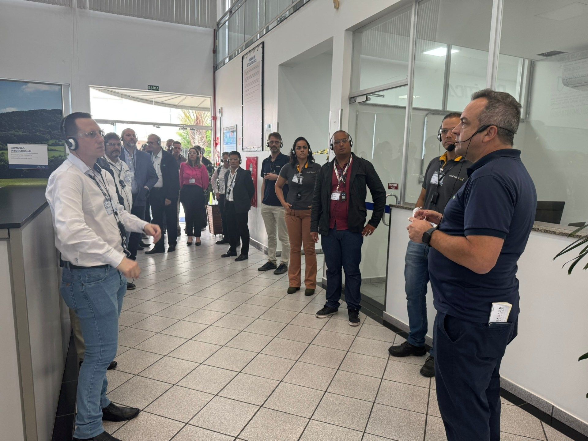 Um grupo de pessoas está parado em um corredor conversando entre si.