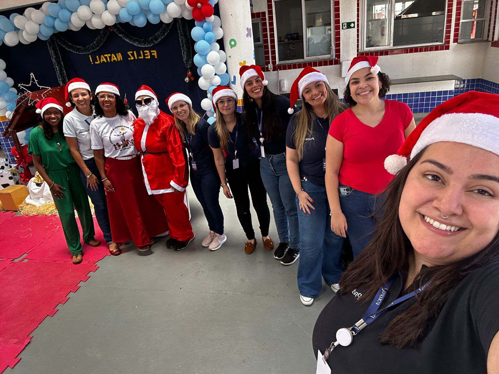 Um grupo de pessoas usando chapéus de Papai Noel estão posando para uma foto.