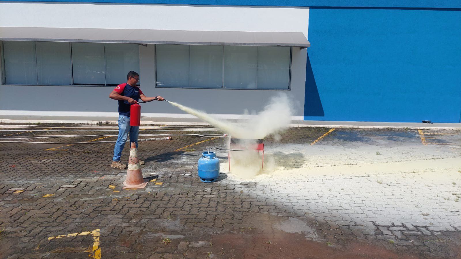 Um homem está usando um extintor de incêndio para apagar um incêndio em um estacionamento