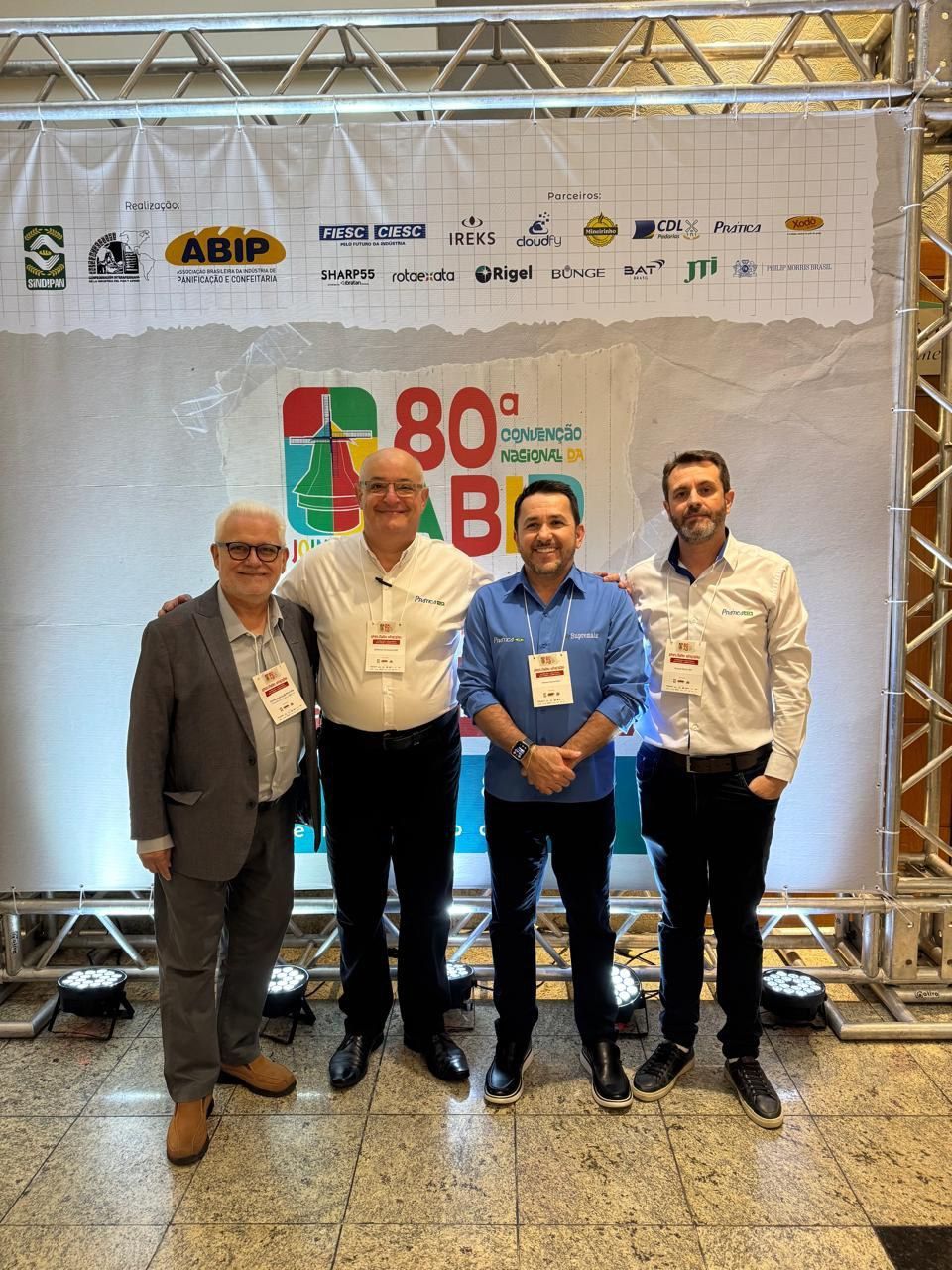 Um grupo de homens está posando para uma foto em frente a uma placa que diz 80.