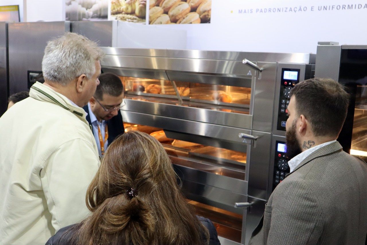 Um grupo de pessoas está olhando para um forno de aço inoxidável.