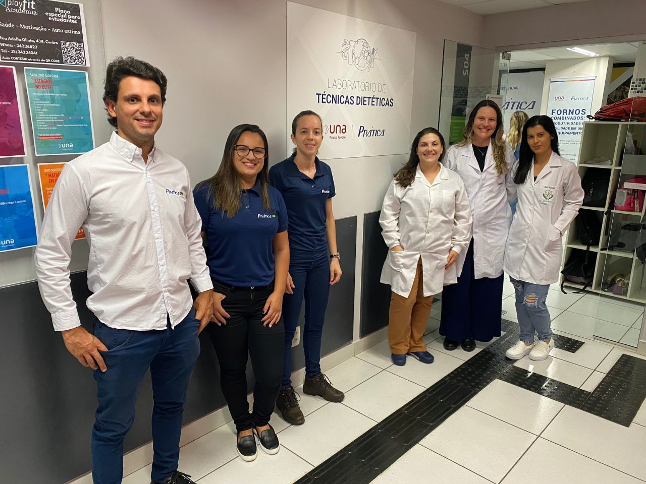 Um grupo de pessoas em pé, uma ao lado da outra, em um corredor.