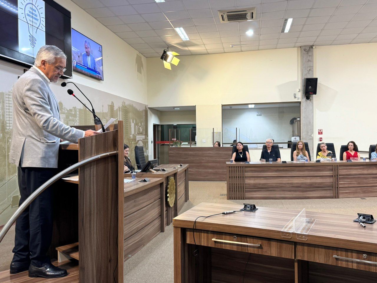 Um homem está em um pódio fazendo um discurso em uma sala de conferências.