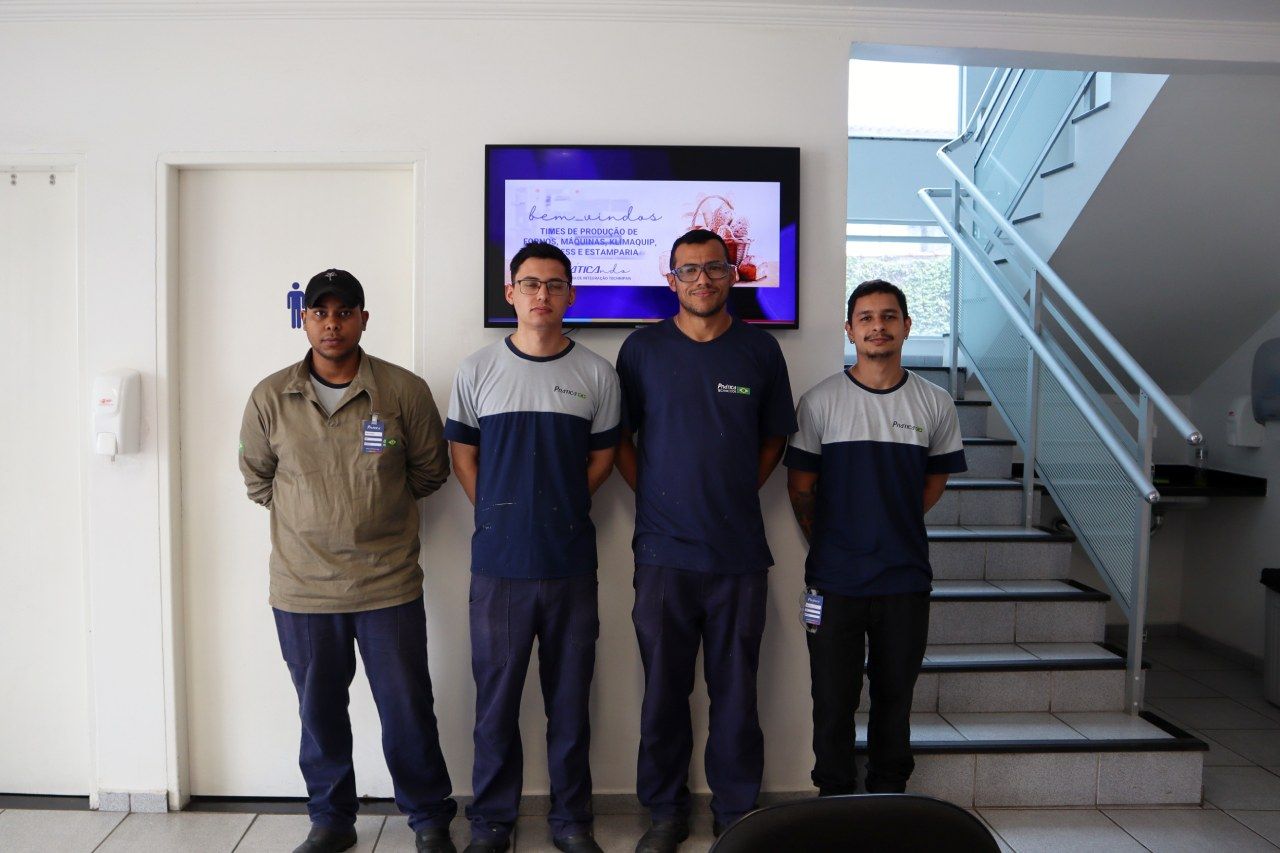 Um grupo de homens está posando para uma foto em frente a uma tv