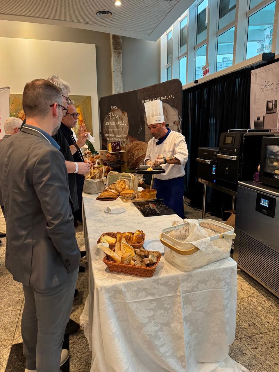 Um homem de terno está em pé em frente a uma mesa com comida.