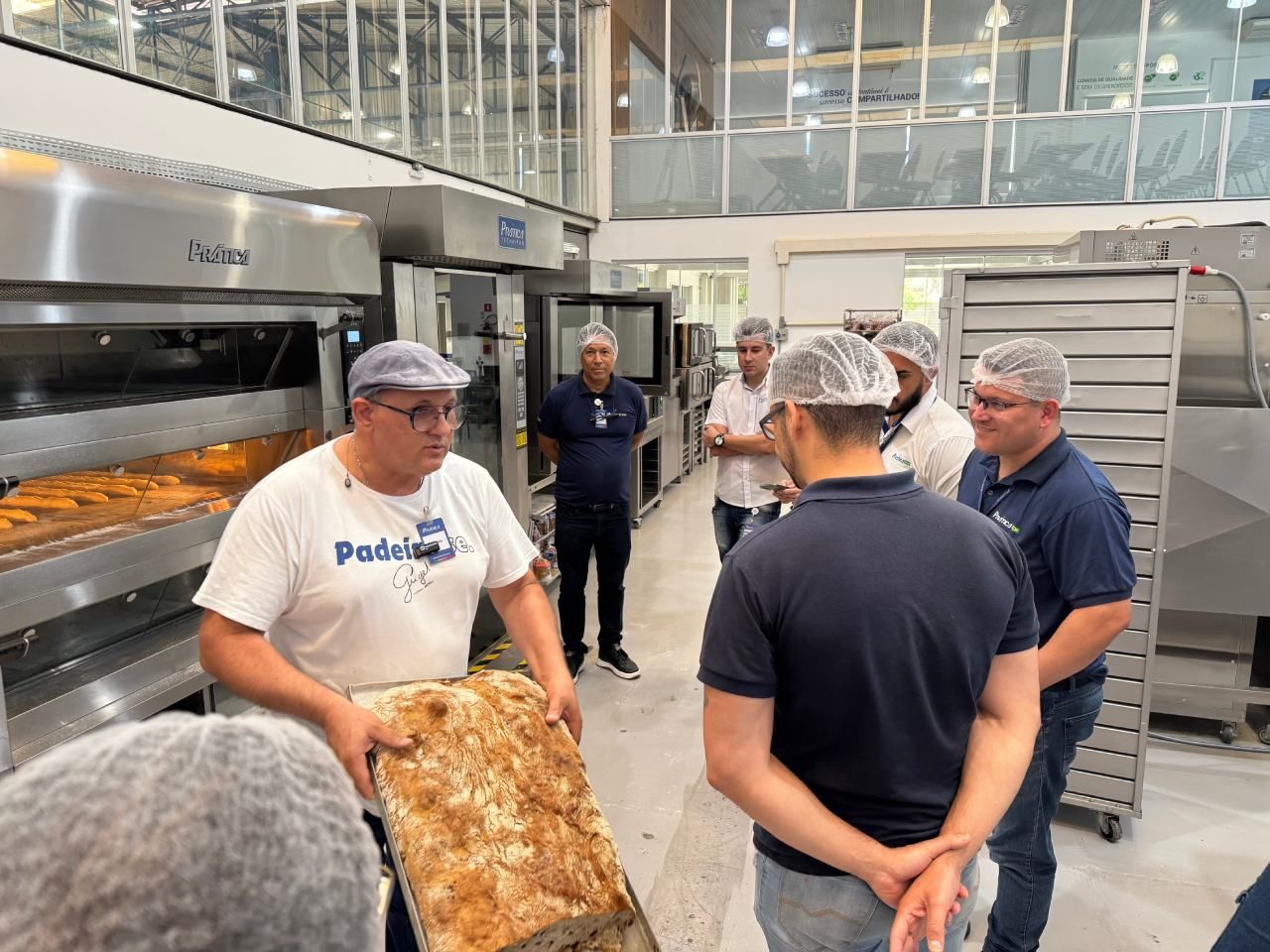 Um grupo de homens está em volta de um homem segurando um pedaço de pão.