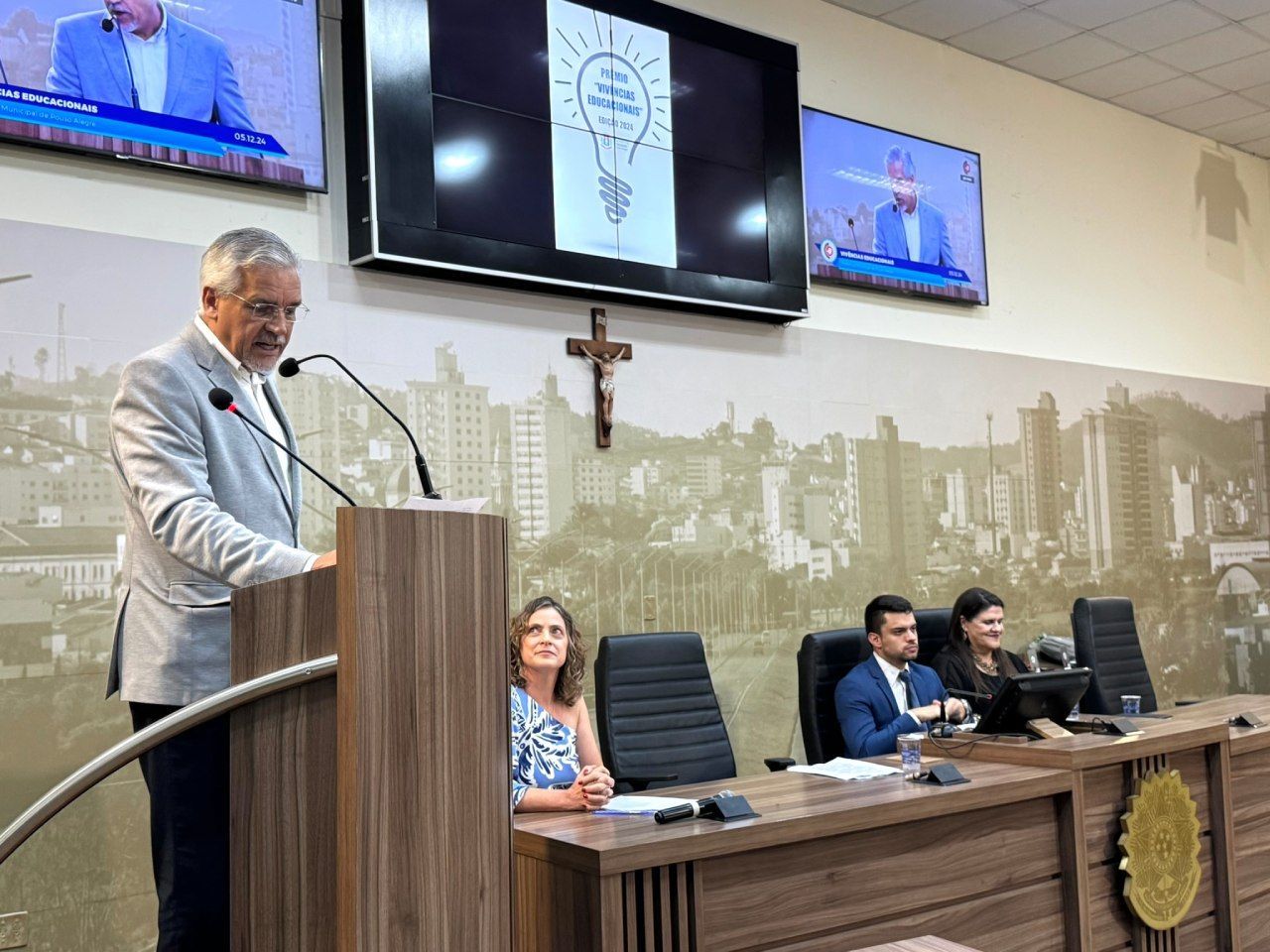 Um homem está em um pódio fazendo um discurso na frente de um grupo de pessoas.