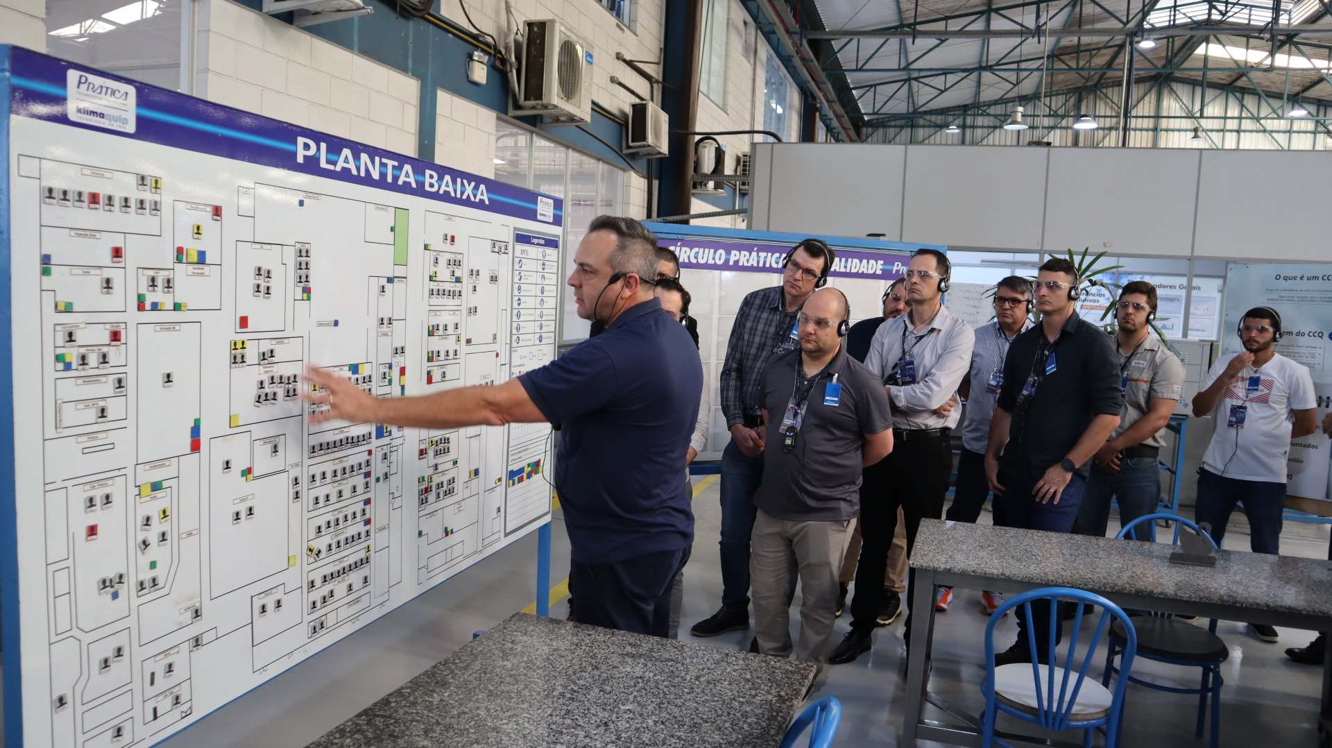 Um grupo de homens está olhando para um quadro branco em uma fábrica.