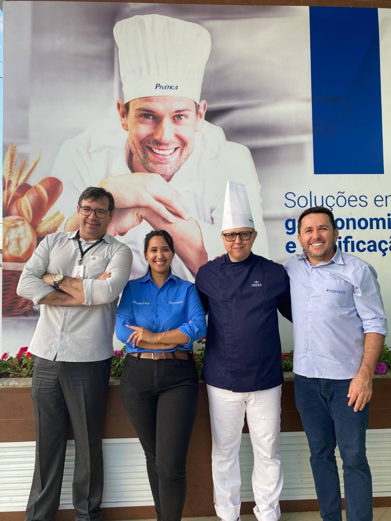 Um grupo de pessoas posando em frente à foto de um chef