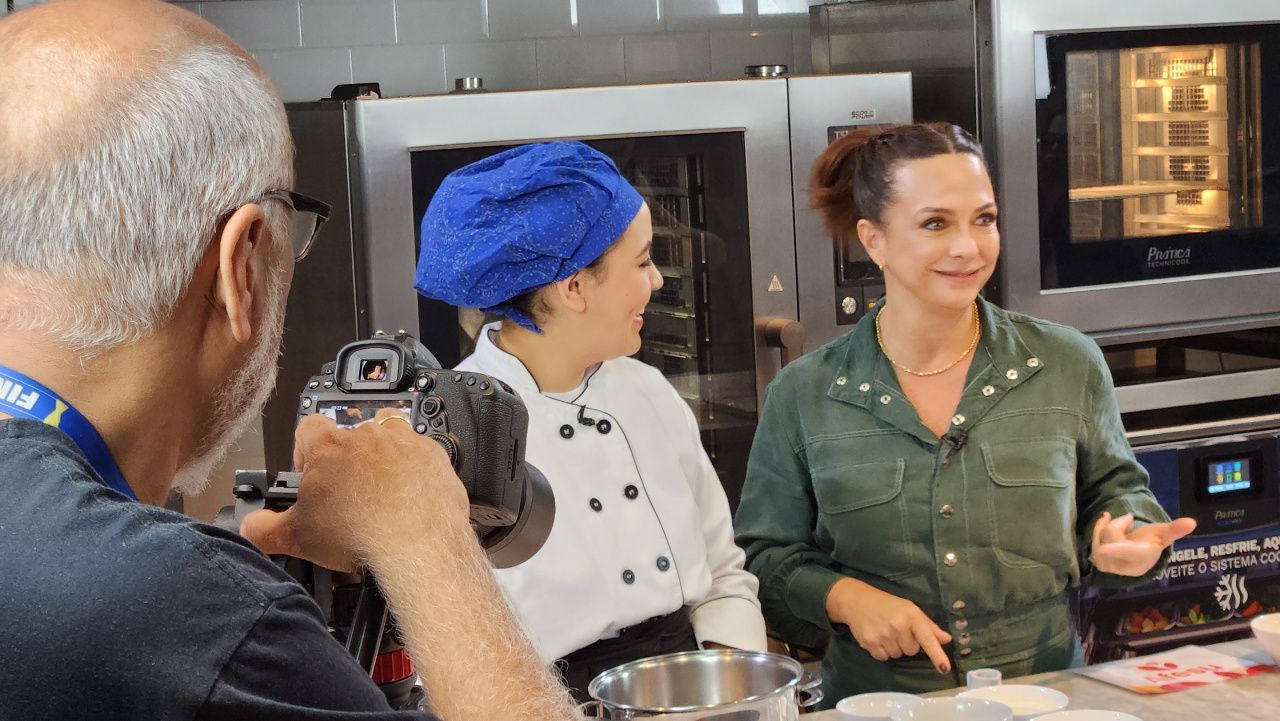 Um homem está tirando uma foto de duas mulheres em uma cozinha.