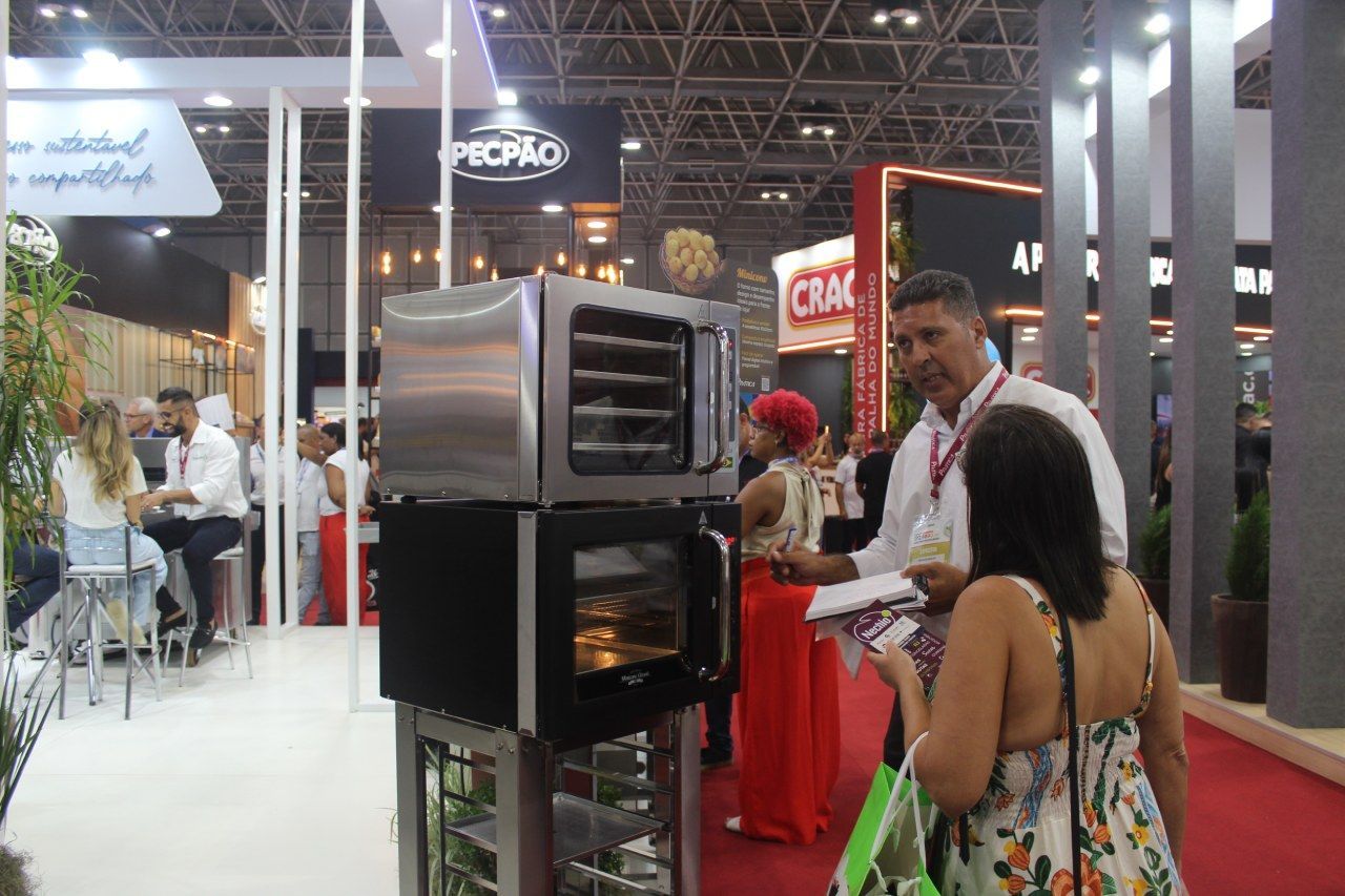 Um grupo de pessoas está ao redor de um estande em uma convenção.