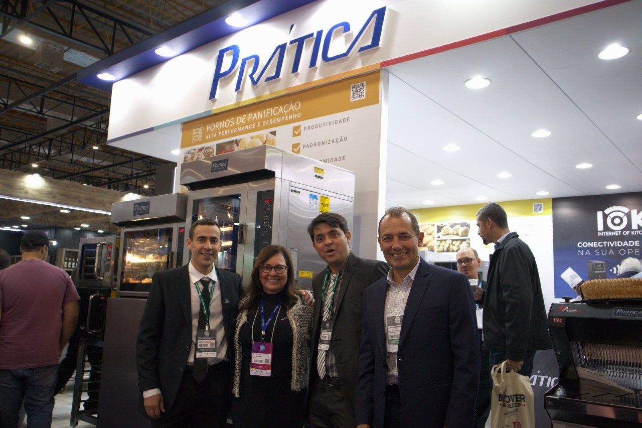 Um grupo de pessoas está posando para uma foto em frente a uma placa de prática.