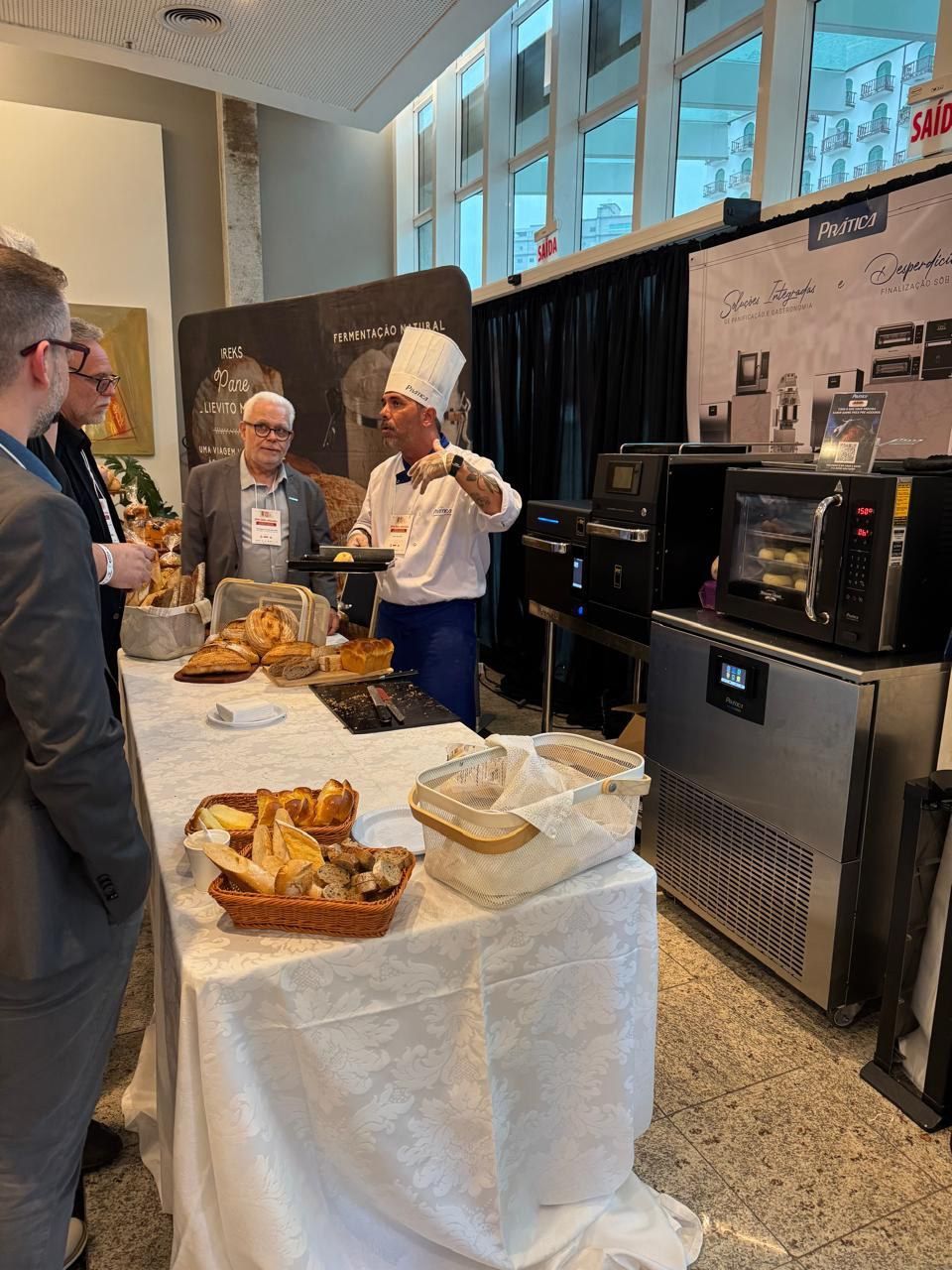 Um grupo de pessoas está em pé ao redor de uma mesa com comida.
