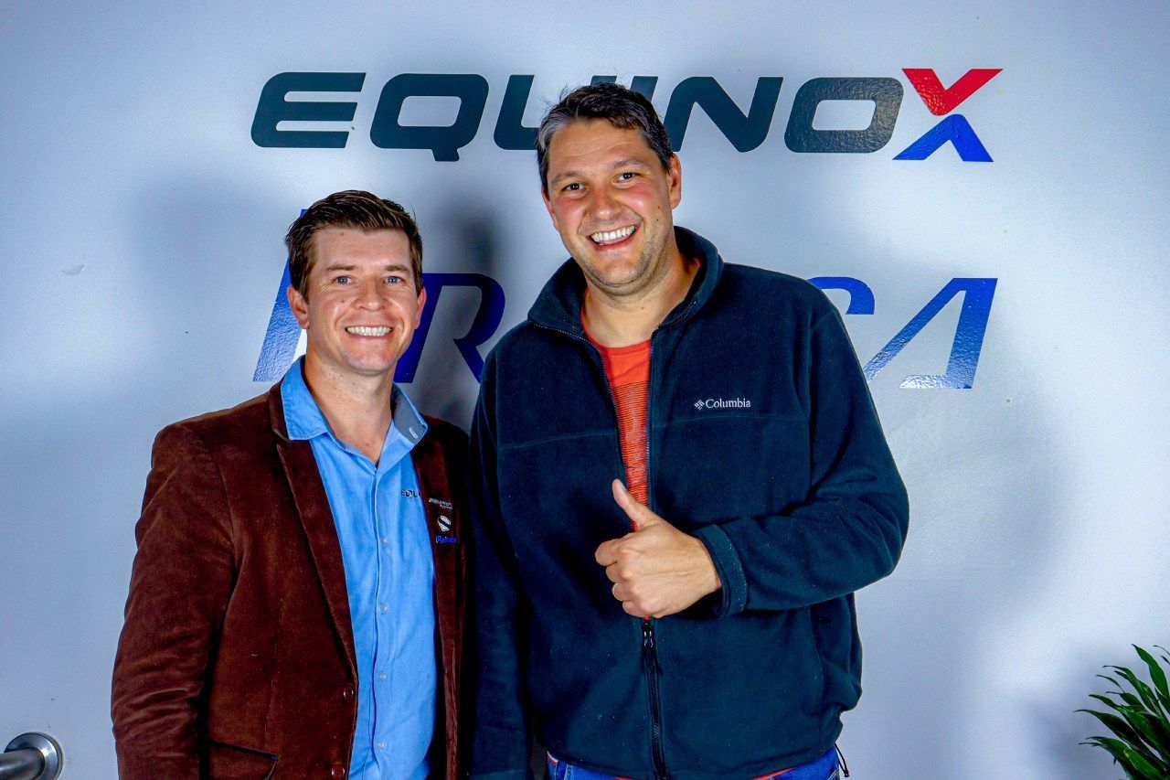 Dois homens posando para uma foto em frente a um sinal de equinócio