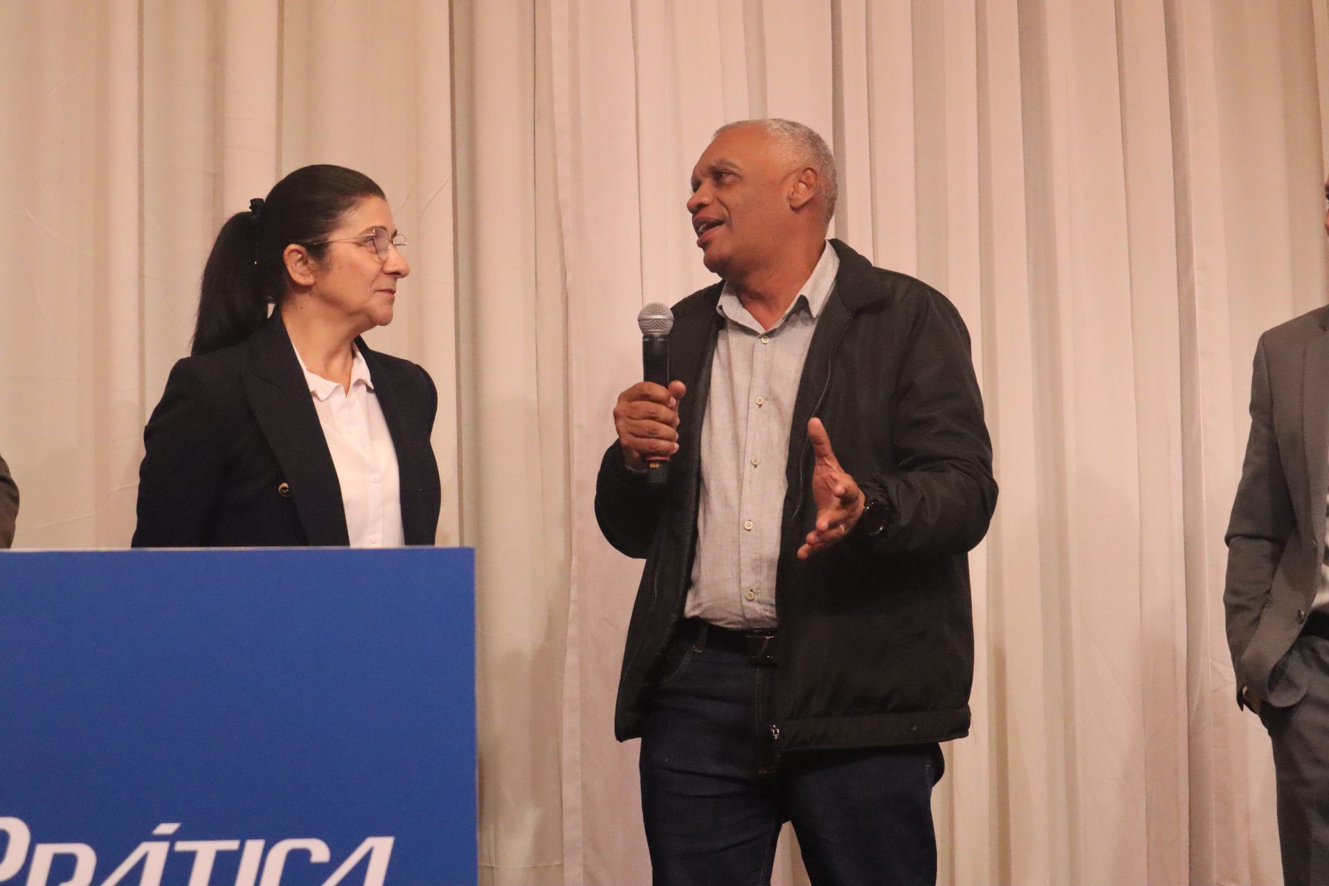 Um homem segura um microfone enquanto está ao lado de uma mulher.