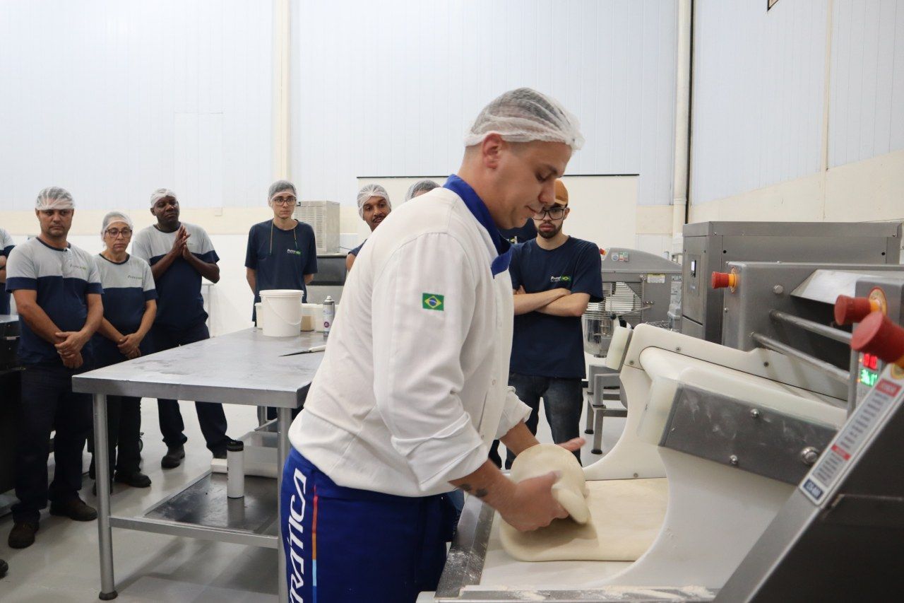 Um homem de camisa branca e calça azul está trabalhando em uma máquina