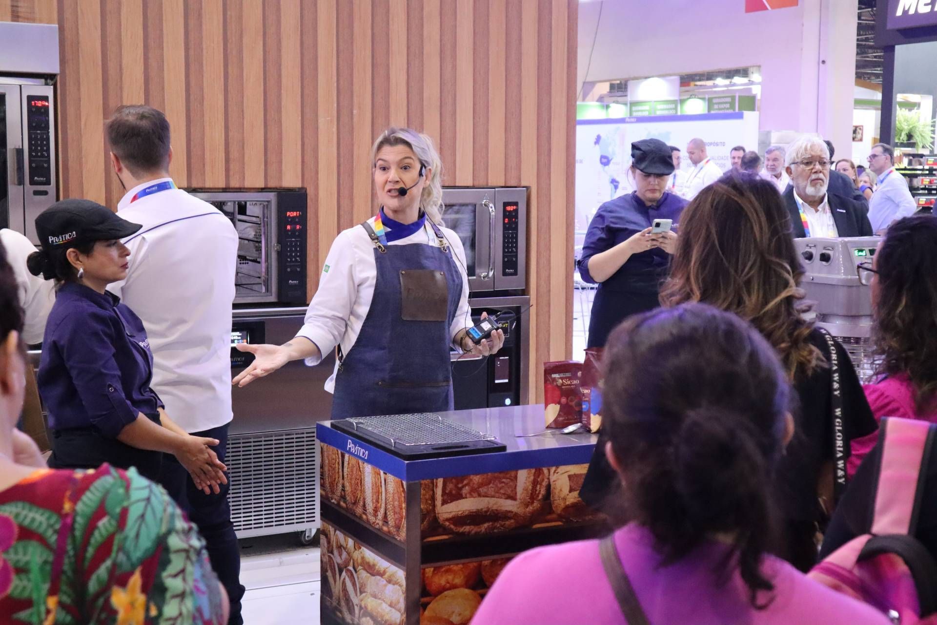 Uma mulher está fazendo uma apresentação para um grupo de pessoas em uma padaria.