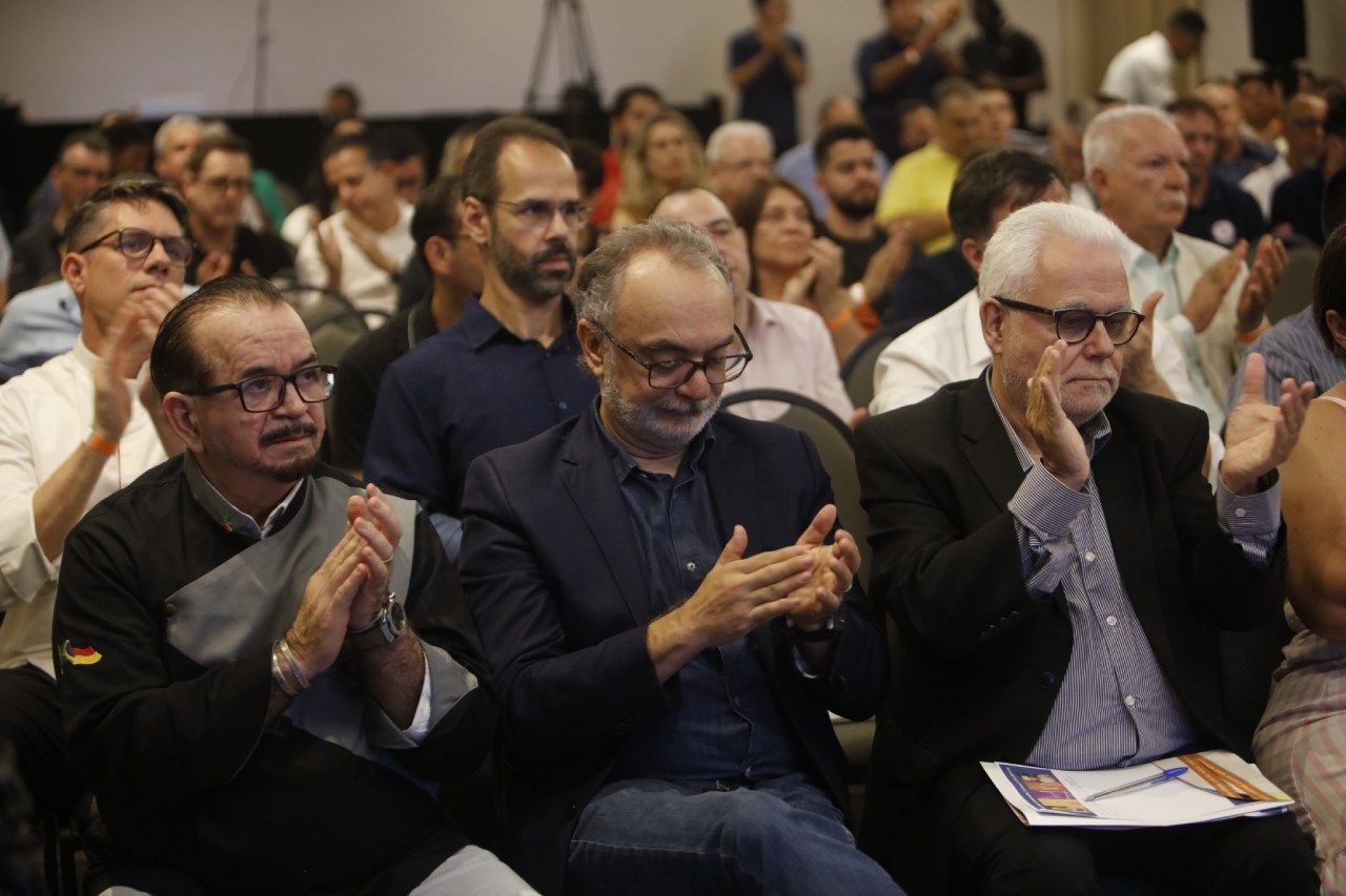 Um grupo de pessoas está sentado em uma sala batendo palmas.