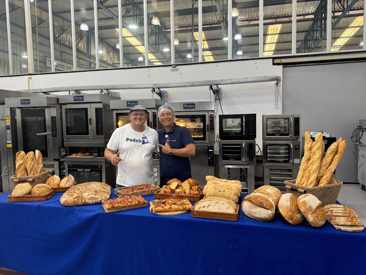 Dois homens estão de pé em frente a uma mesa cheia de pão.