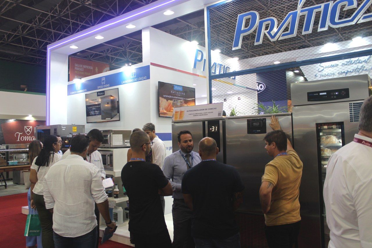 Um grupo de pessoas está diante de uma geladeira de aço inoxidável.