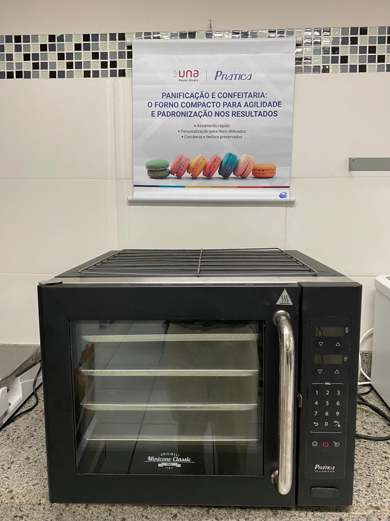 Um forno preto está sobre um balcão ao lado de um pôster na parede.