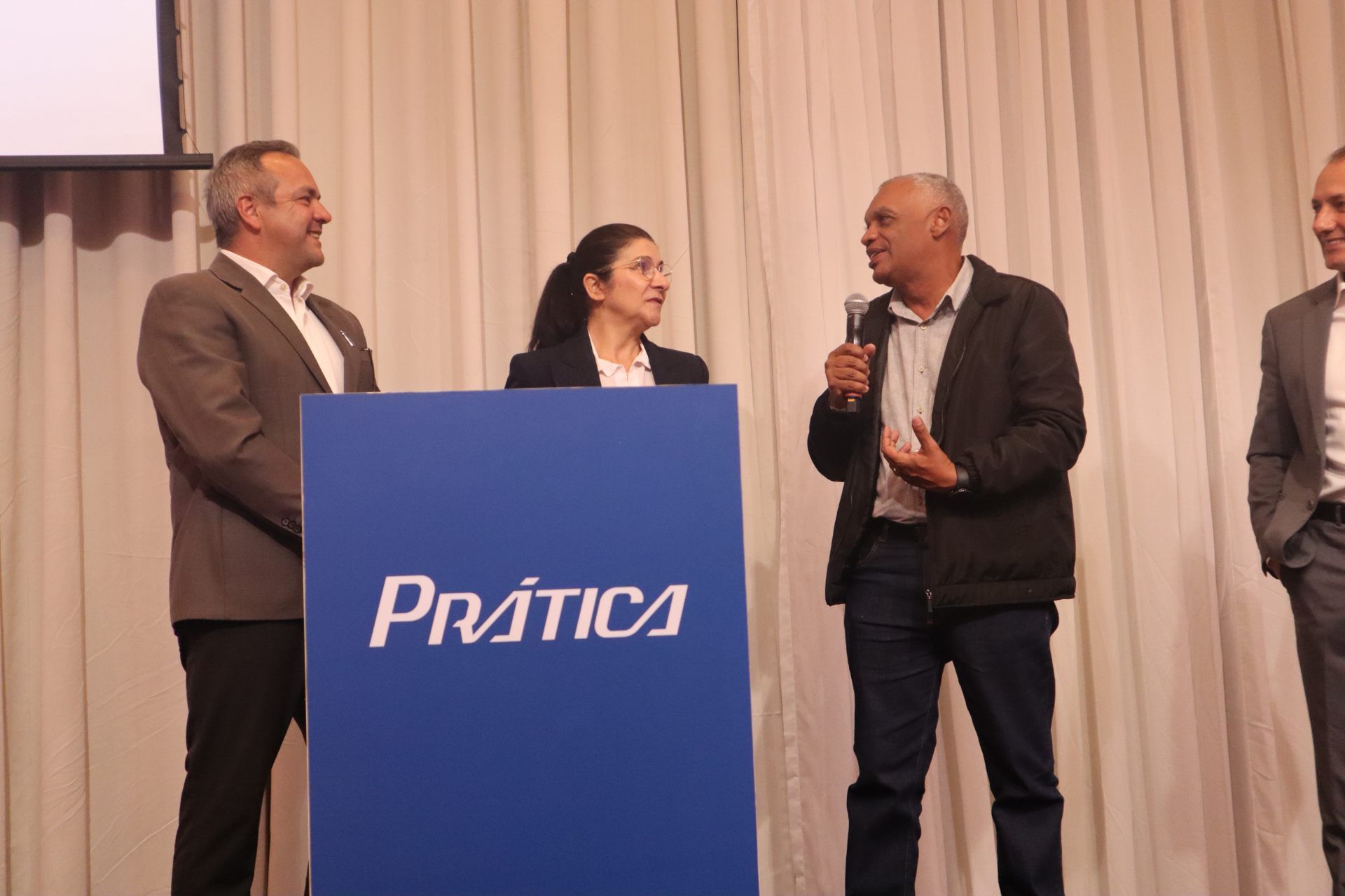 Um grupo de pessoas em pé ao redor de um pódio que diz pratica