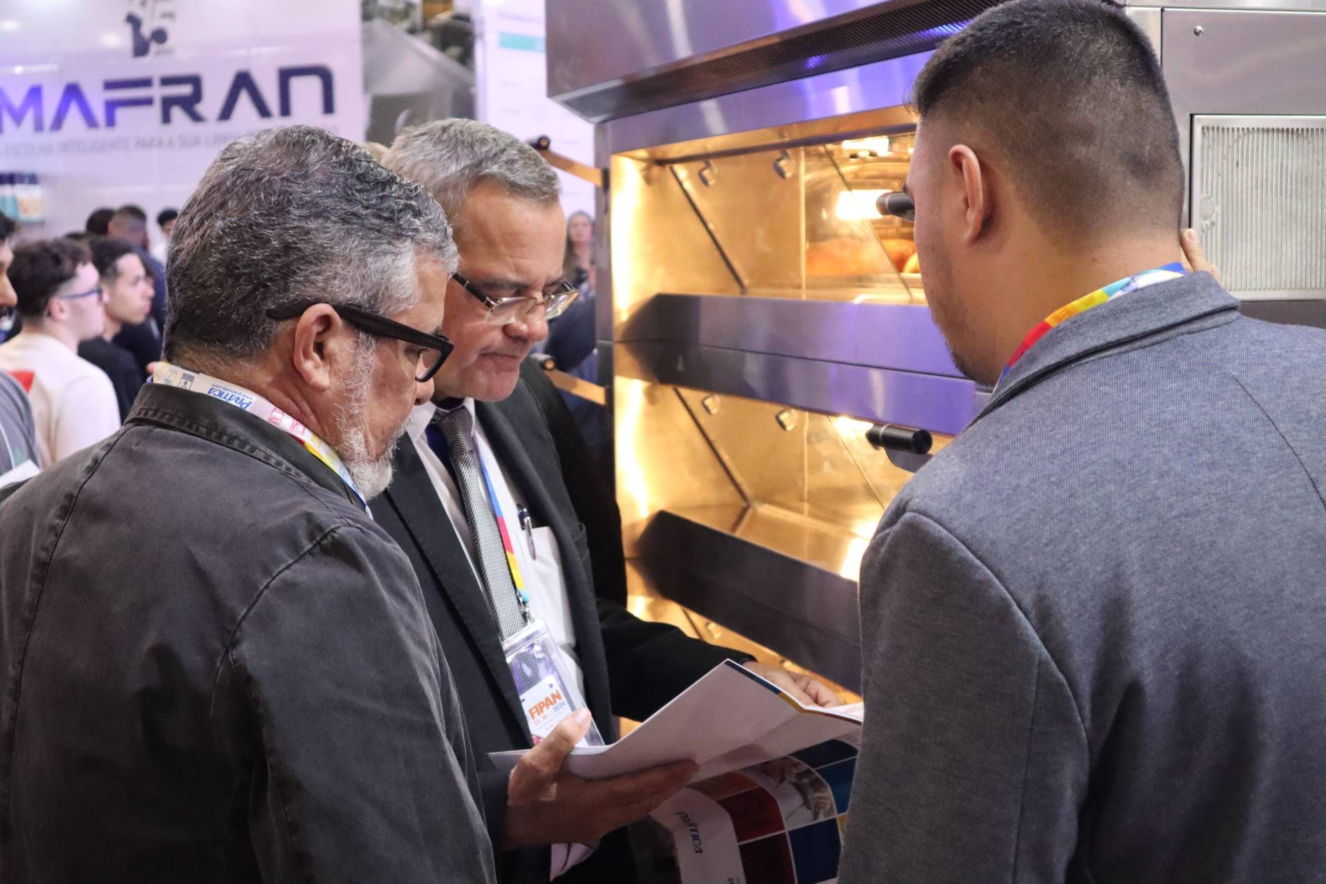 Um grupo de homens está em frente a um forno olhando para um pedaço de papel.