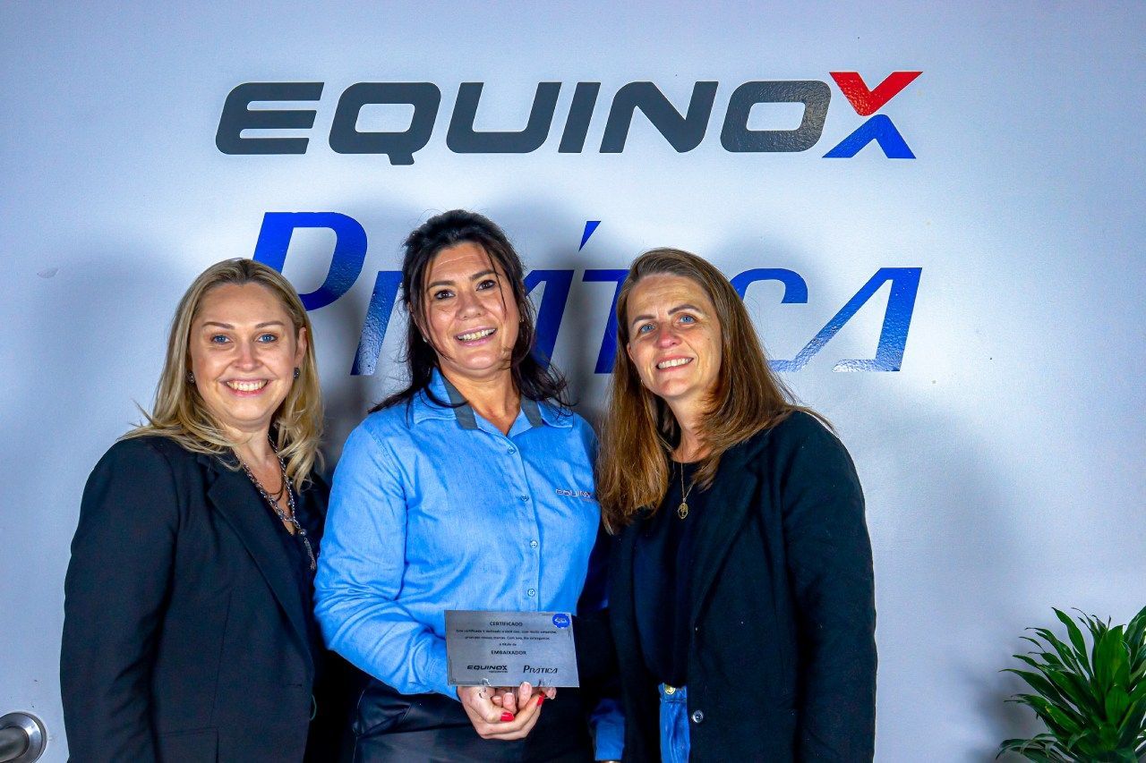 Três mulheres estão posando para uma foto em frente a um signo de equinócio.