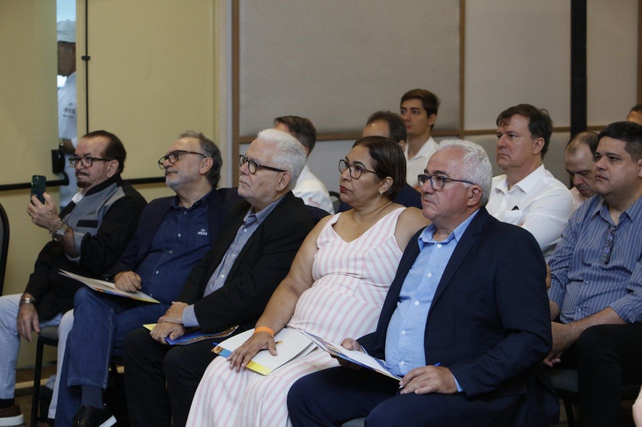 Um grupo de pessoas está sentado em uma sala assistindo a uma apresentação.