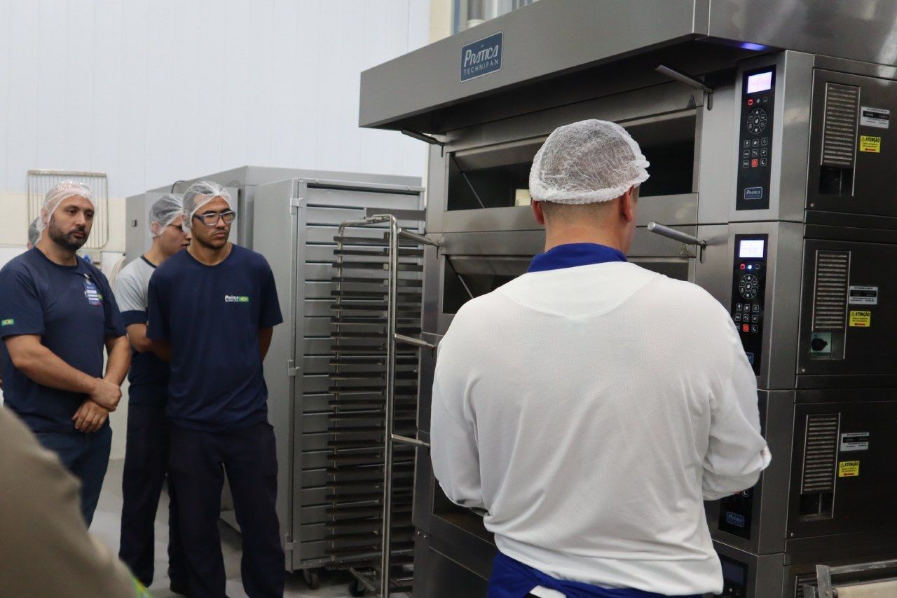 Um homem de camisa branca está parado em frente a um forno.
