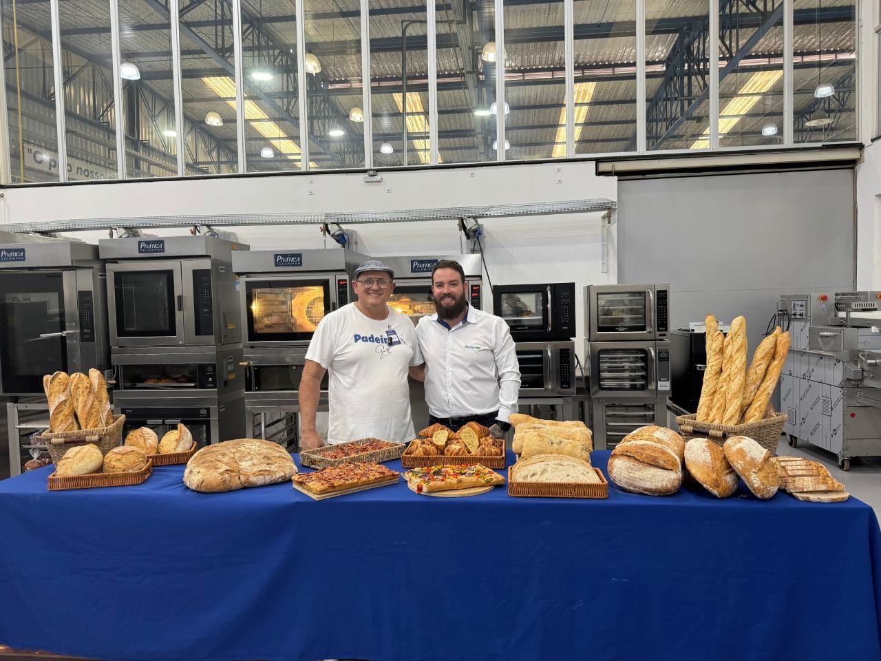 Dois homens estão de pé em frente a uma mesa cheia de pão.