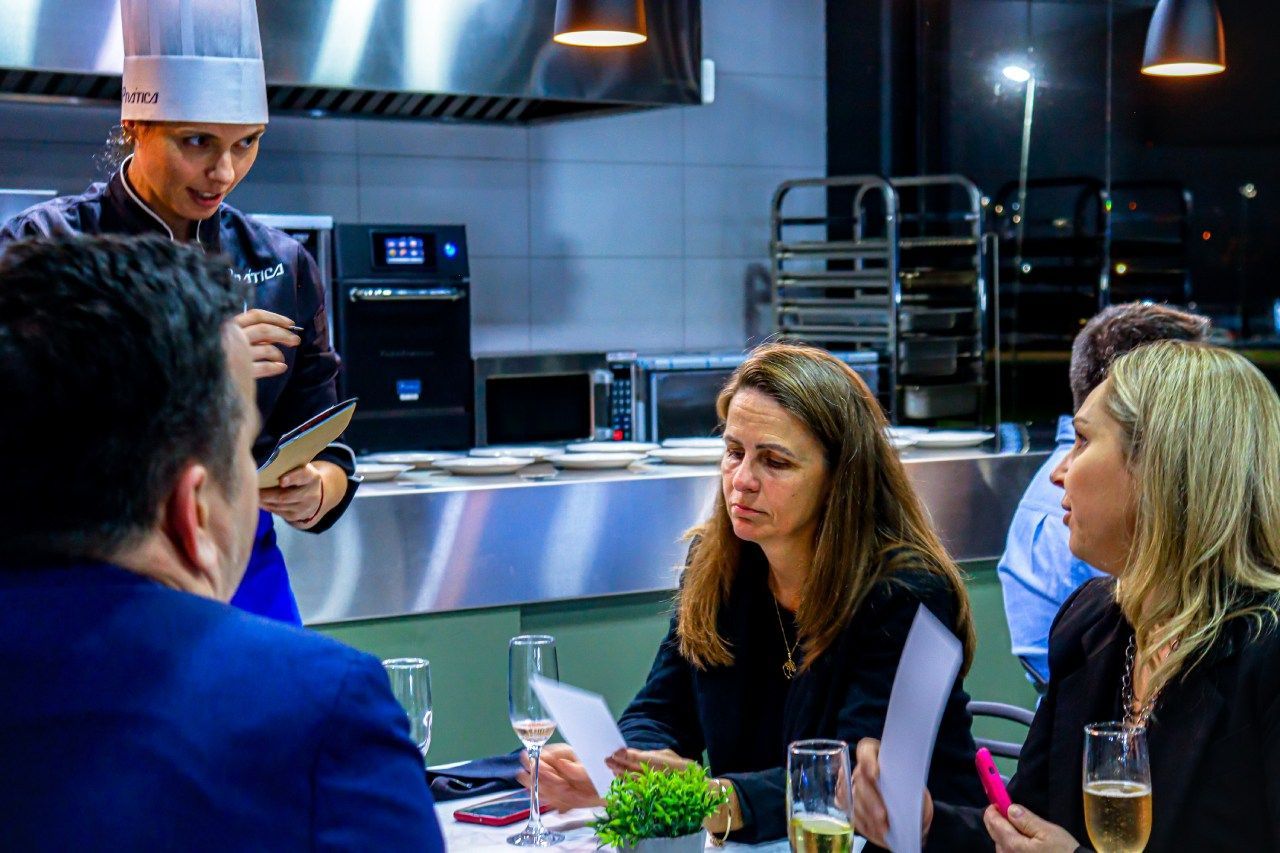 Um grupo de pessoas está sentado à mesa na cozinha.