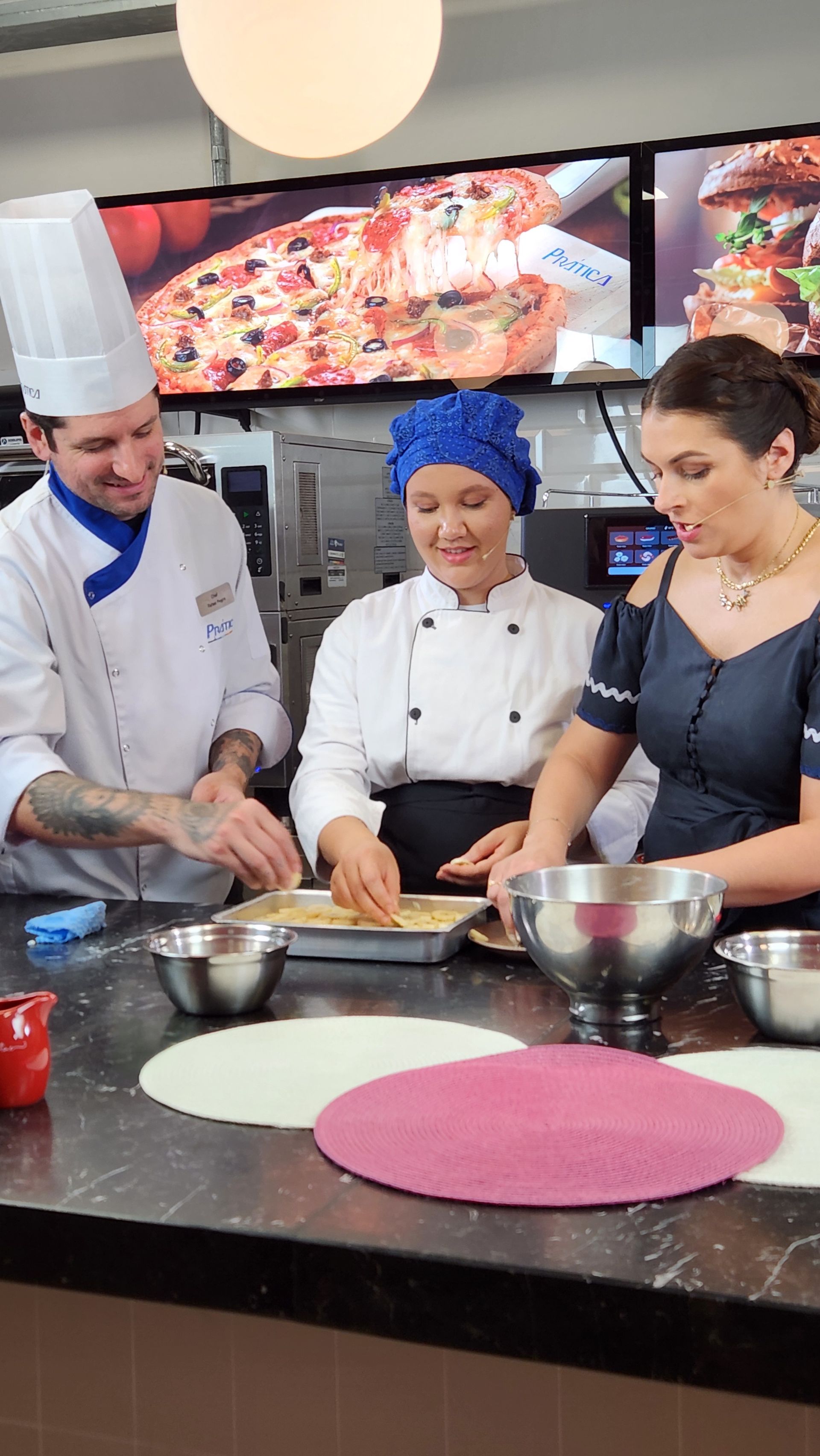 Um homem e duas mulheres estão preparando pizza em uma cozinha
