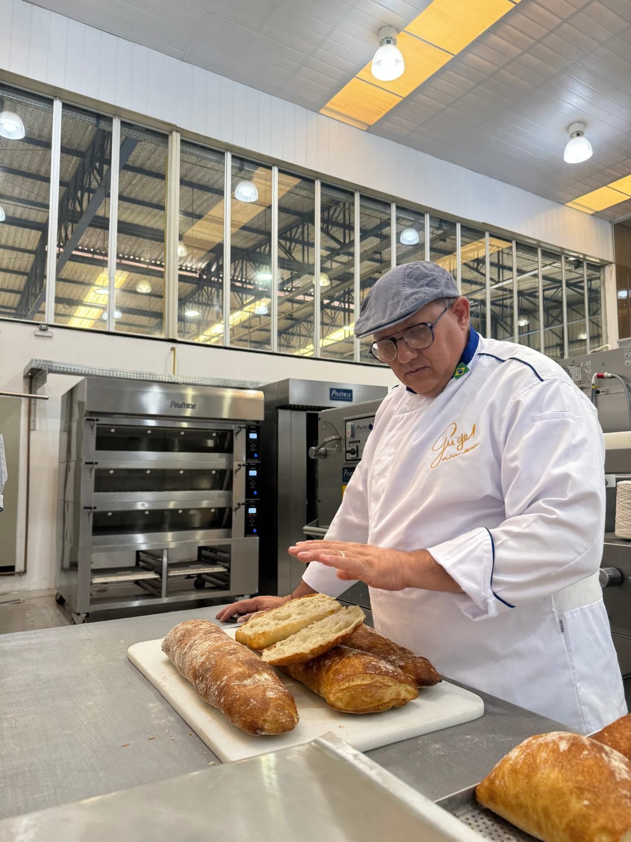 Um homem está cortando pão em uma tábua de corte em uma padaria.