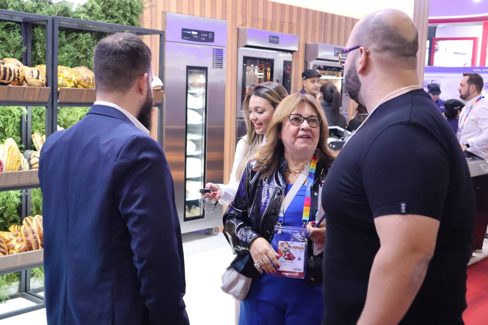 Um grupo de pessoas está em volta de uma padaria conversando entre si.