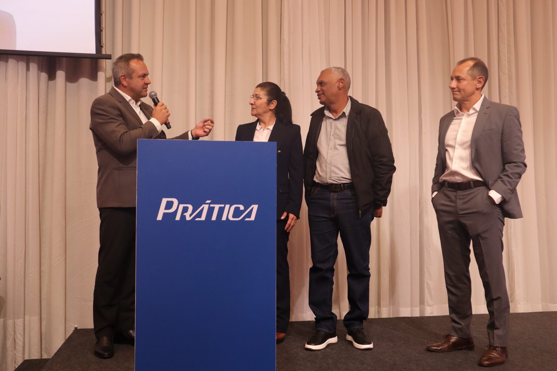 Um grupo de pessoas em pé ao redor de um pódio que diz prática