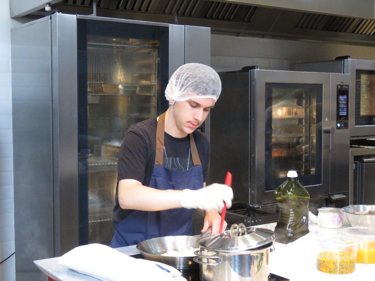 Um homem está cozinhando em uma cozinha usando uma rede de cabelo