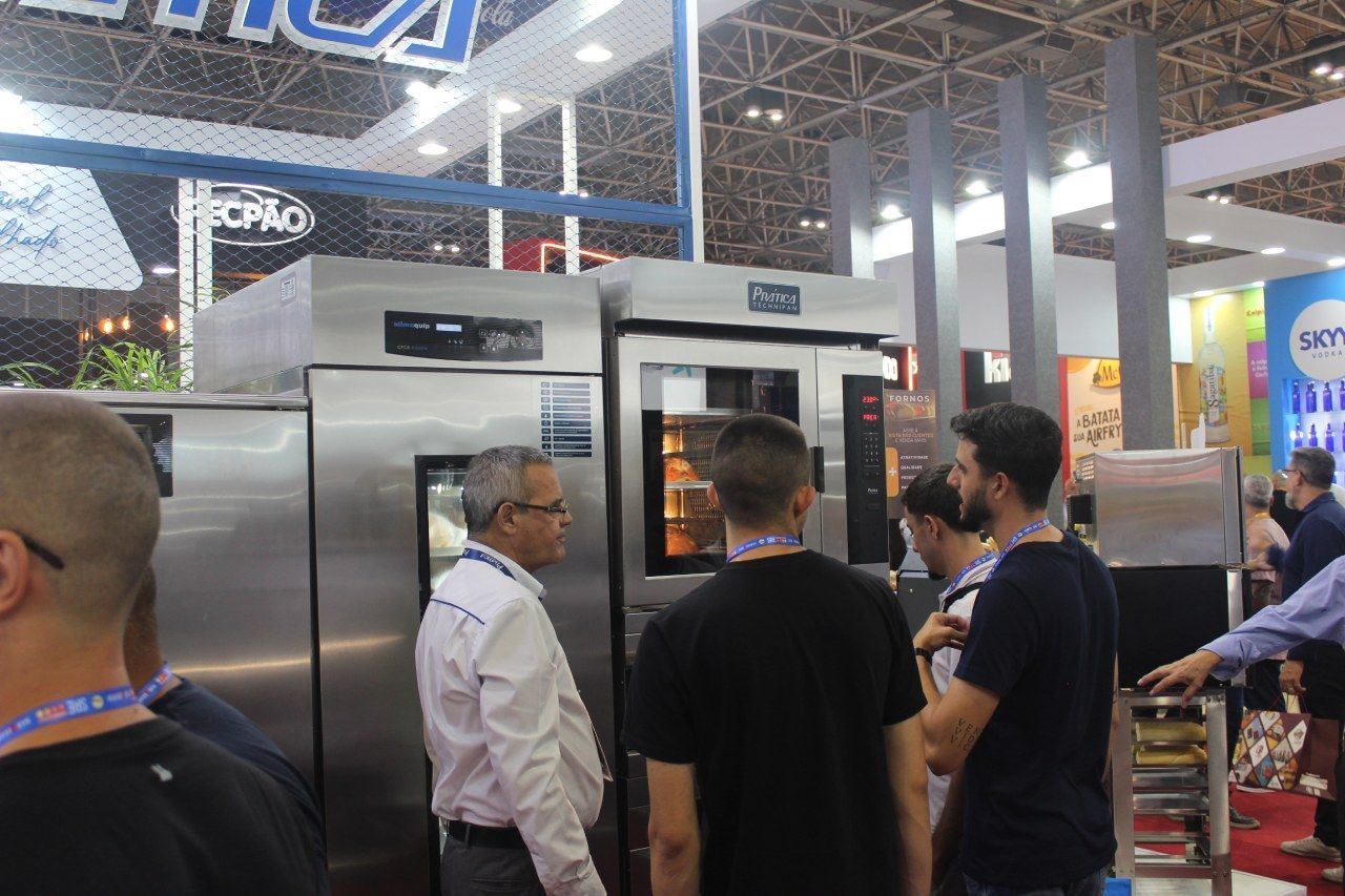 Um grupo de pessoas está em volta de um forno de aço inoxidável.