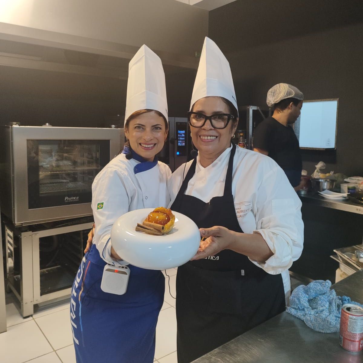Duas chefs femininas posando para uma foto em uma cozinha