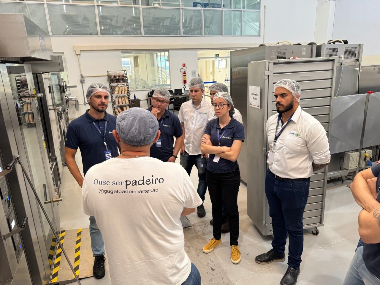 Um homem está conversando com um grupo de pessoas em uma cozinha.