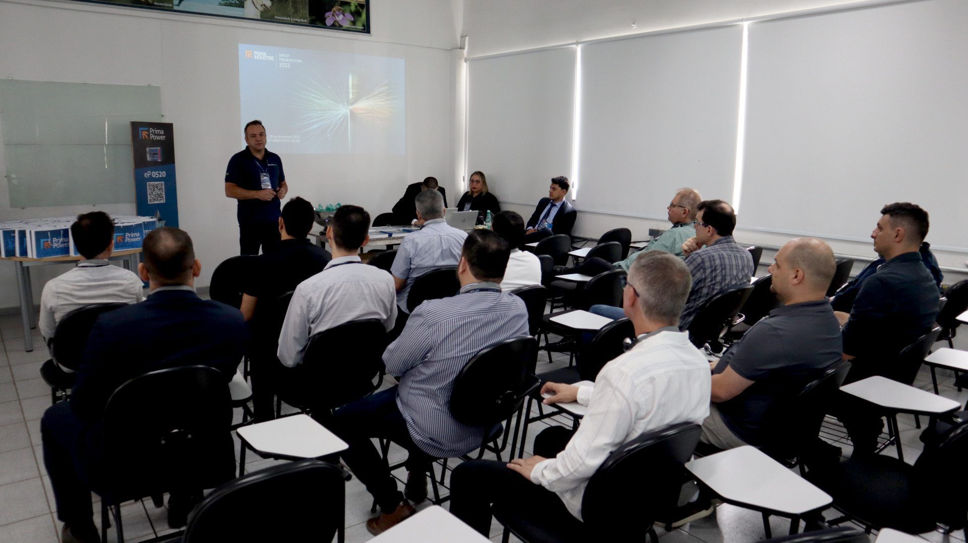 Um grupo de homens está sentado em uma sala de aula ouvindo uma apresentação.