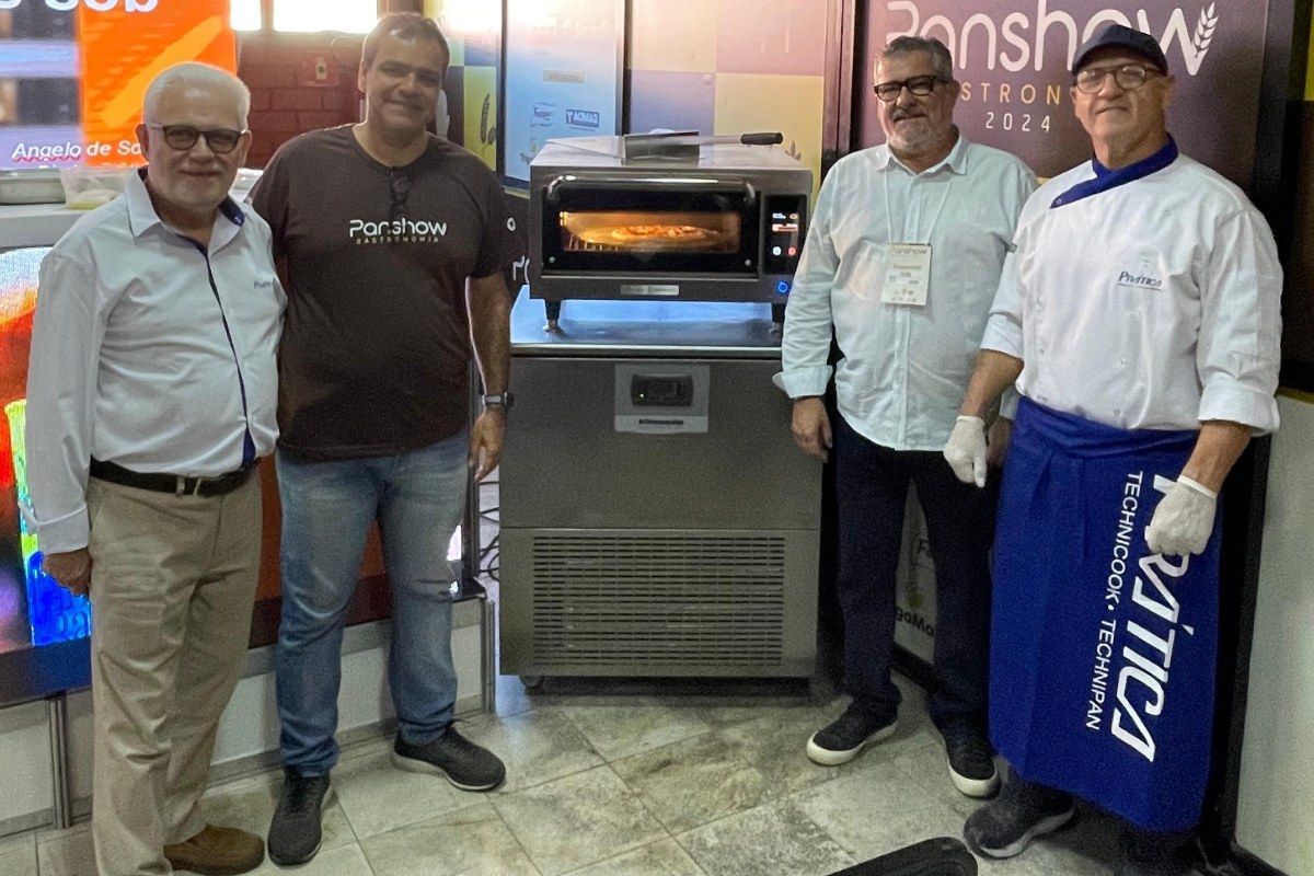 Um grupo de homens está em frente a um forno de pizza.