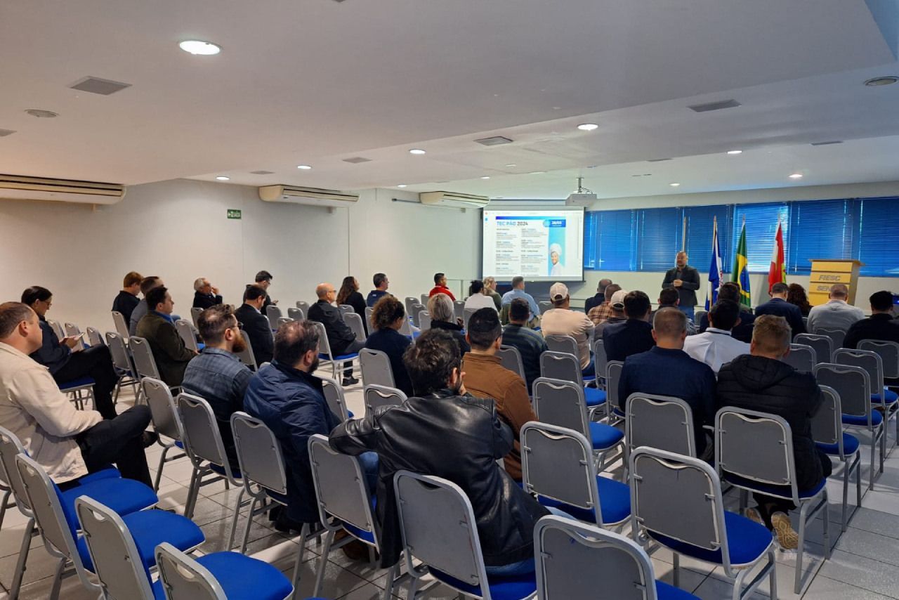 Um grupo de pessoas está sentado em cadeiras em uma sala de conferências.