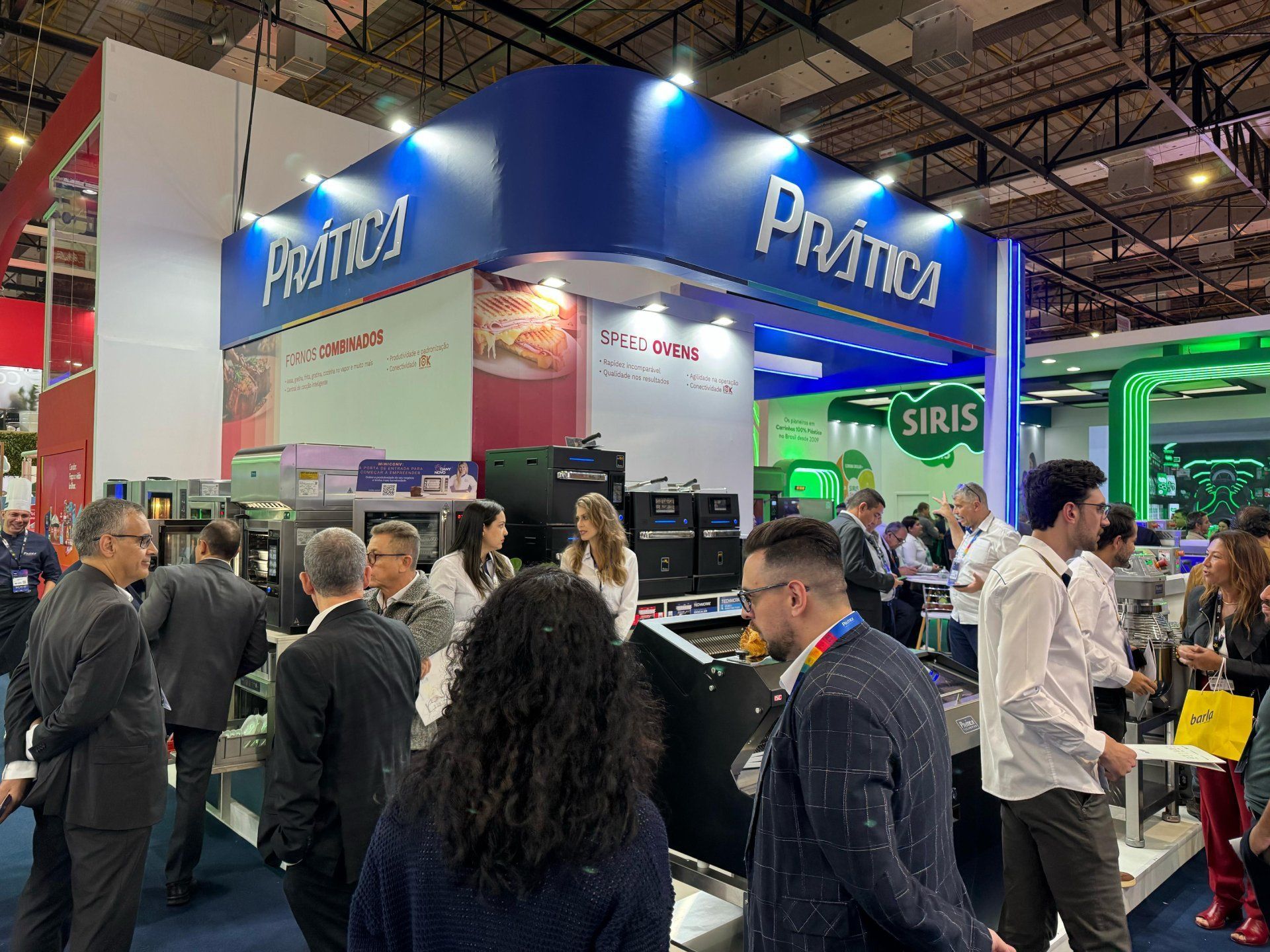 Um grupo de pessoas está em volta de um estande em uma convenção.