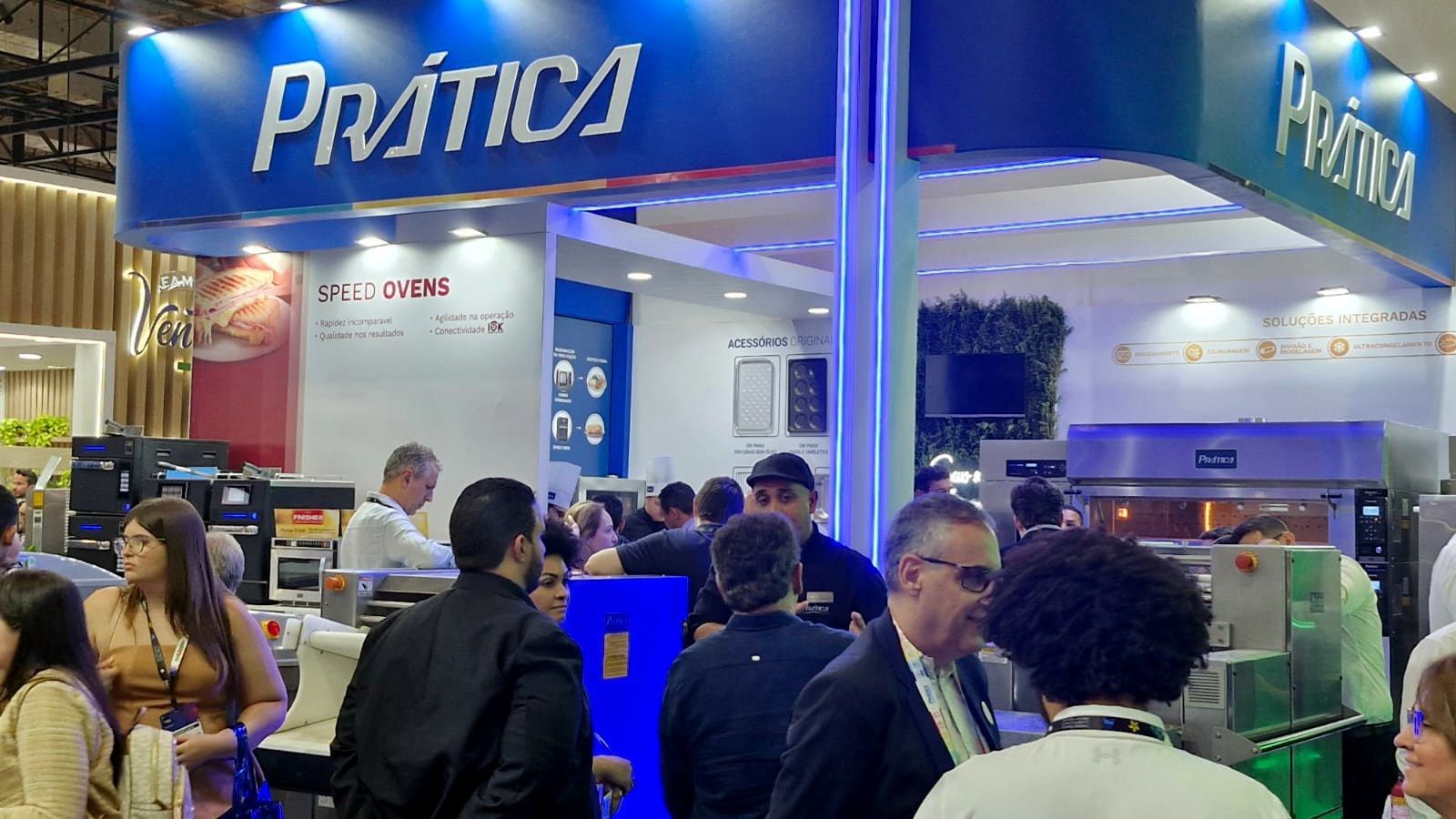 Um grupo de pessoas está em frente a um estande em uma convenção.