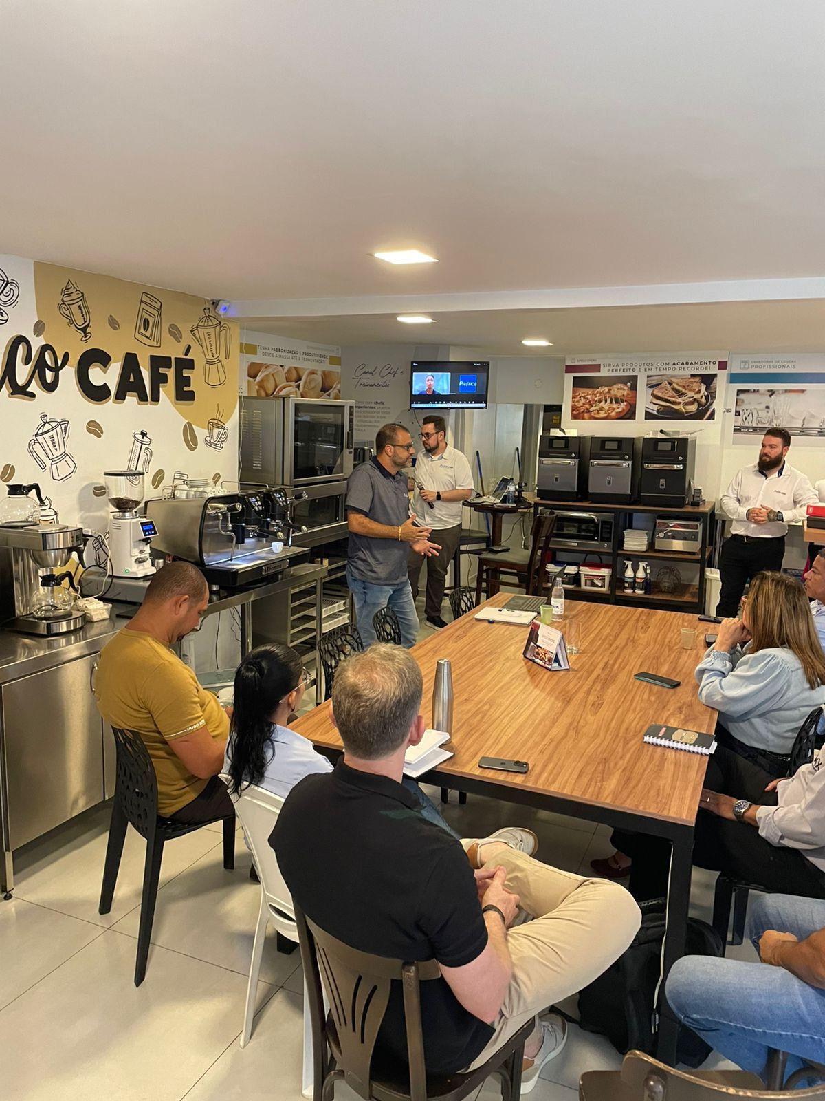 Um grupo de pessoas está sentado ao redor de uma mesa em um restaurante.