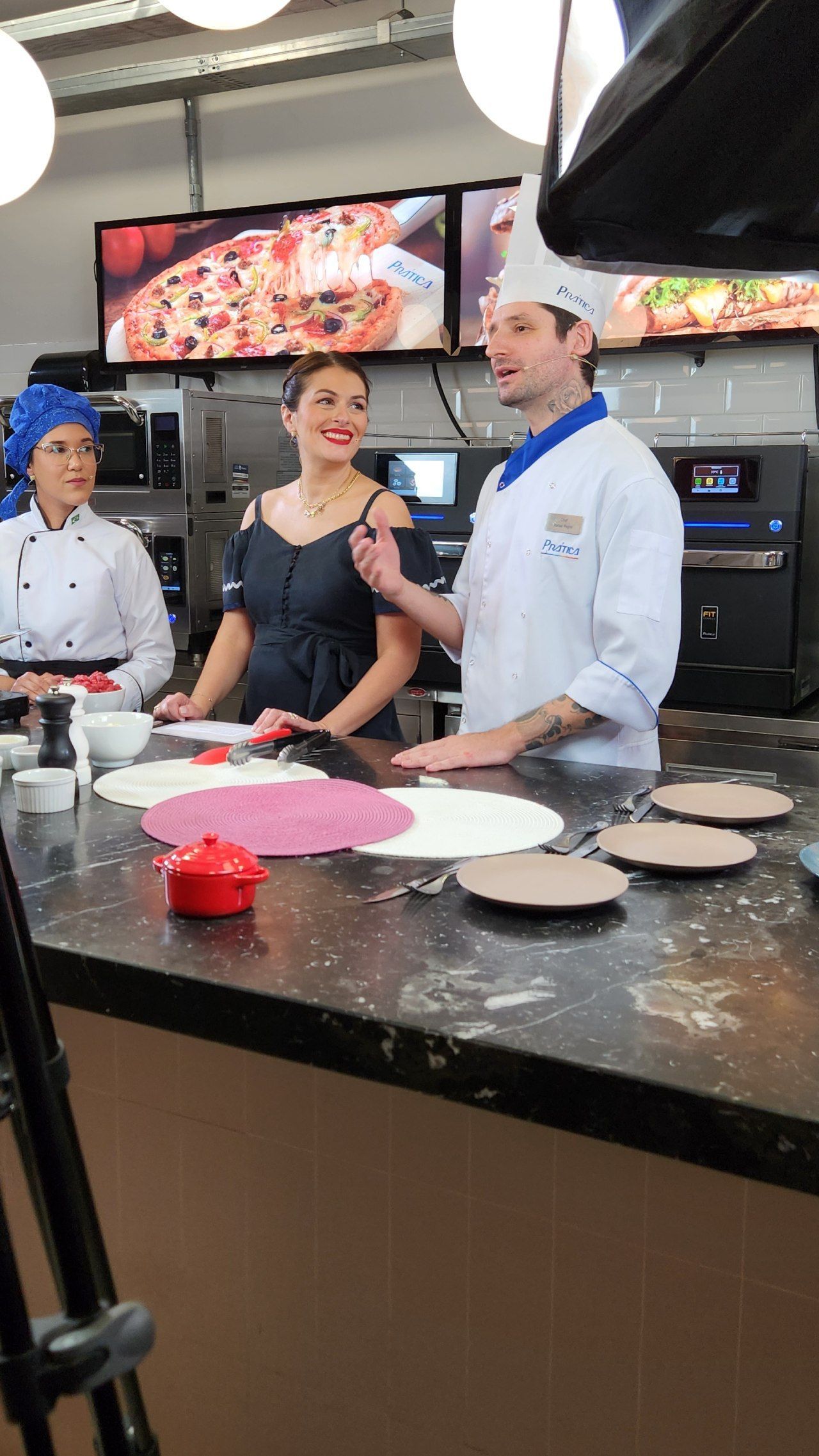 Um grupo de pessoas está em volta de um balcão fazendo pizzas.