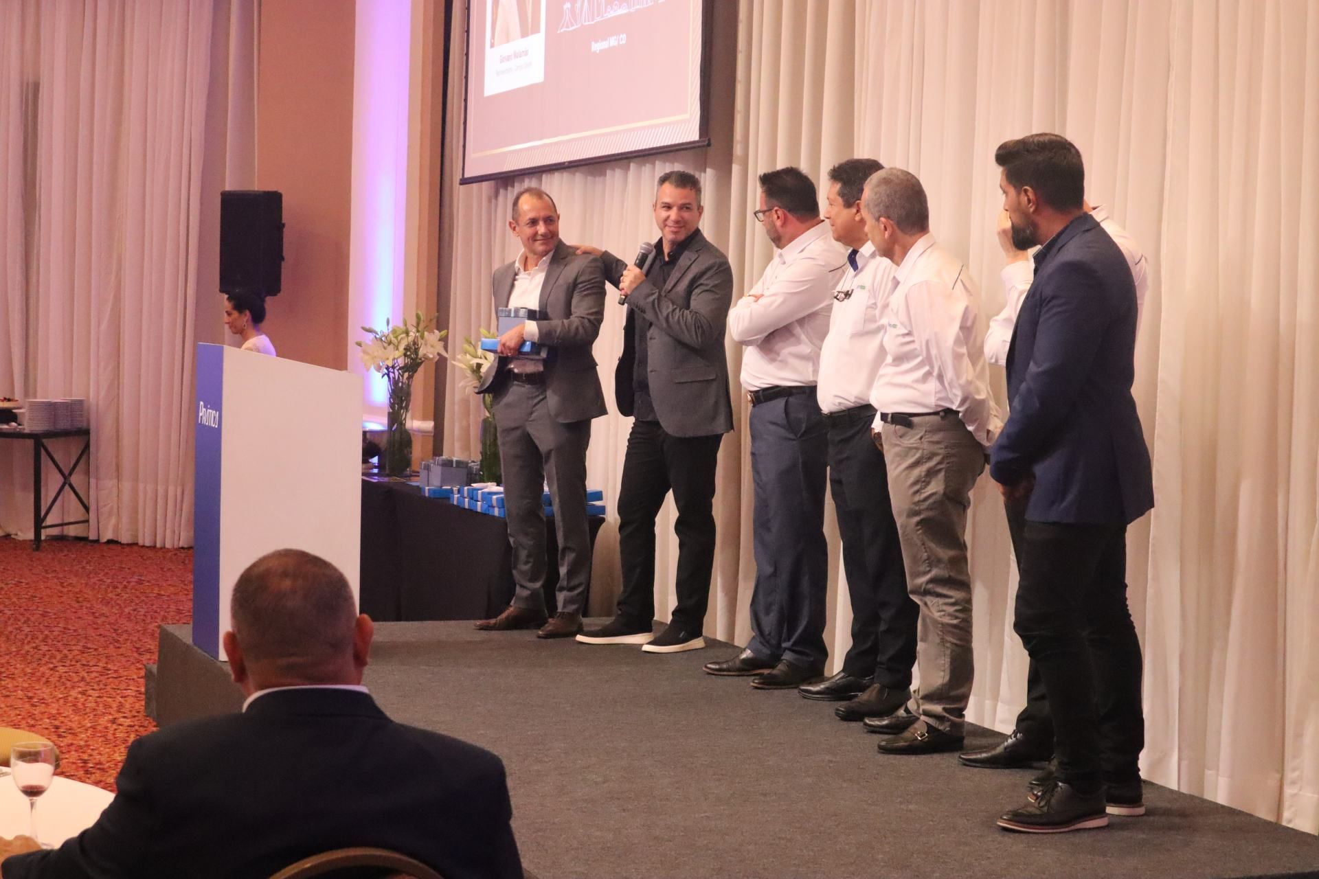 Um grupo de homens está em pé em um palco em frente a um pódio.