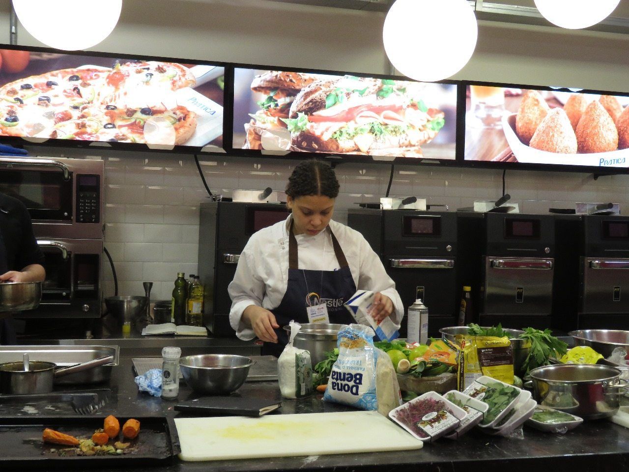 Uma mulher de avental prepara comida em uma cozinha