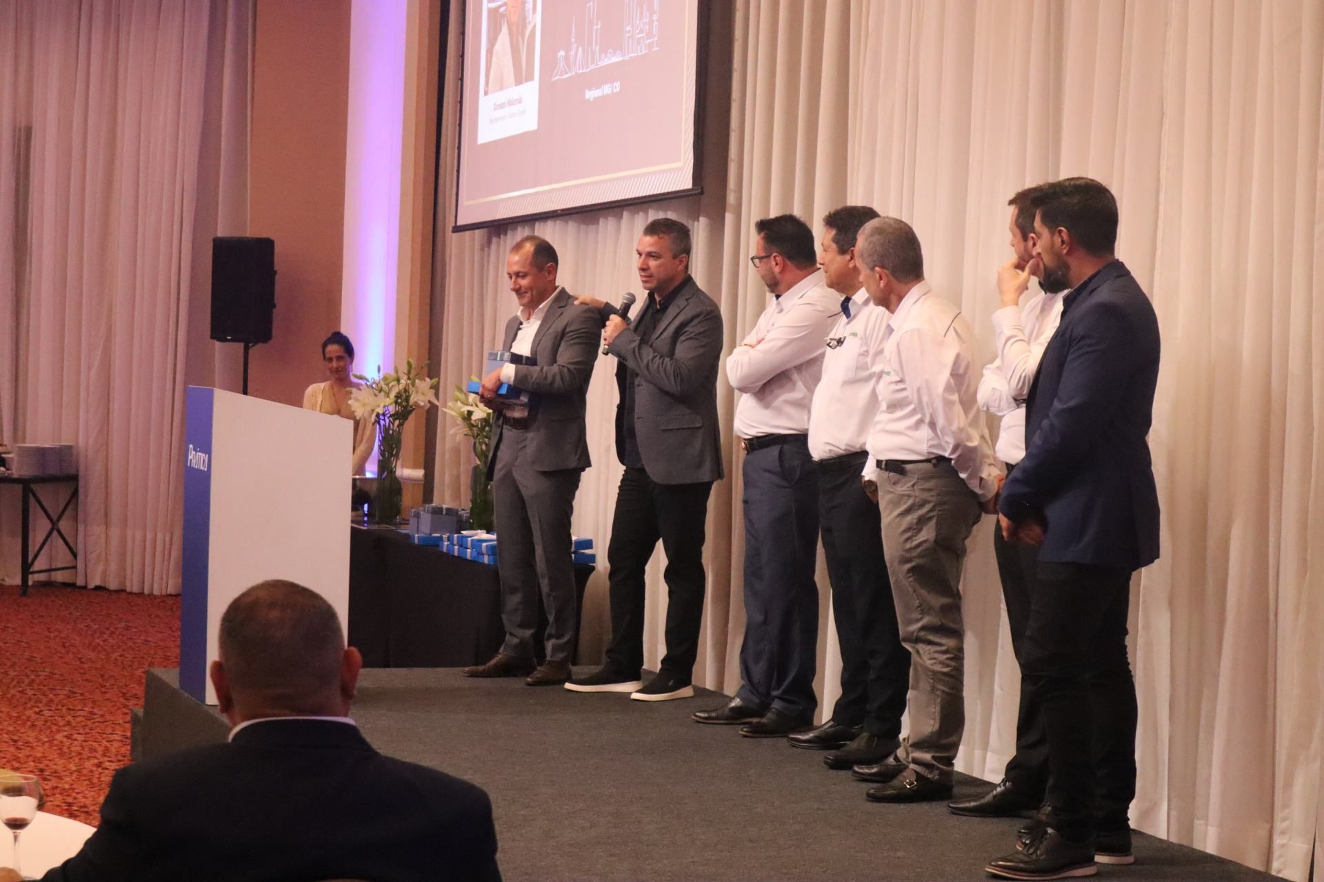 Um grupo de homens está em pé na frente de um pódio em uma conferência.